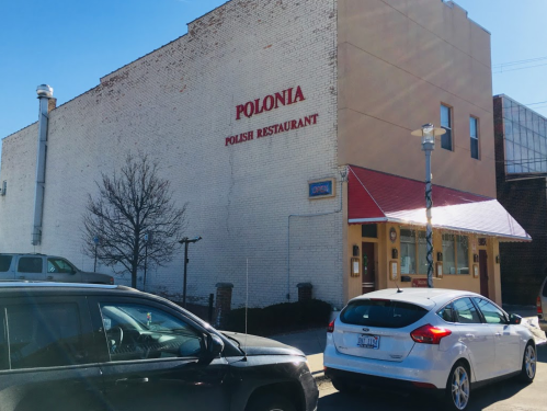 Exterior of Polonia Polish Restaurant with a red sign, "OPEN," and parked cars in front.