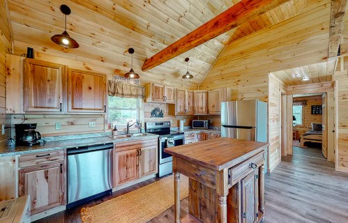 Cozy wooden kitchen with modern appliances, a central island, and rustic decor in a cabin-style setting.