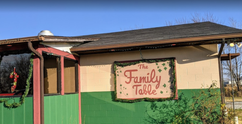 A restaurant building with a sign reading "The Family Table," decorated with greenery and holiday lights.