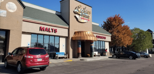 Exterior of a restaurant with a sign reading "Golden Grille," featuring a parking lot and colorful autumn trees.