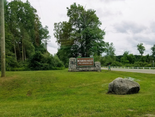 Sign for the Weirdo-Hadley State Recreation Area, surrounded by greenery and a large rock in the foreground.