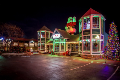 A festive restaurant decorated with colorful lights and a large Christmas tree, set against a night sky.