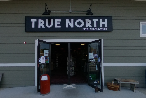 Entrance of a store named "True North," with a sign indicating it's open seven days a week.
