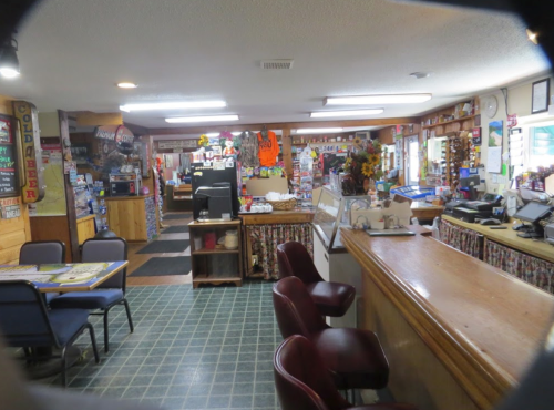 Cozy diner interior with a counter, tables, and colorful decor, featuring a variety of items on display.