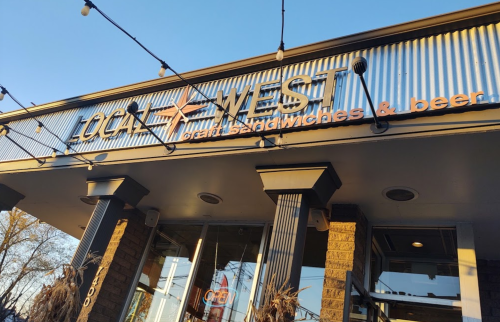Exterior of Local West restaurant, featuring a sign that reads "great sandwiches & beer" with an "OPEN" notice.