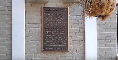 Plaque detailing the history of Cat Alley, mentioning its significance and notable figures in the area.