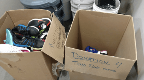 Two cardboard boxes filled with various shoes, labeled for donation to Texas flood victims.