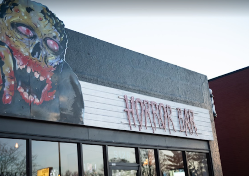 A building exterior featuring a horror-themed mural and a sign that reads "Horror Bar."