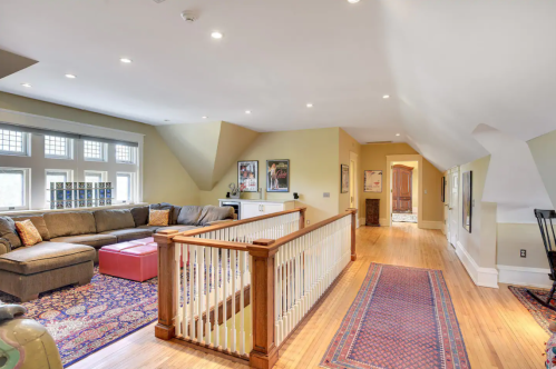 Spacious, well-lit living area with a sectional sofa, colorful rugs, and large windows.