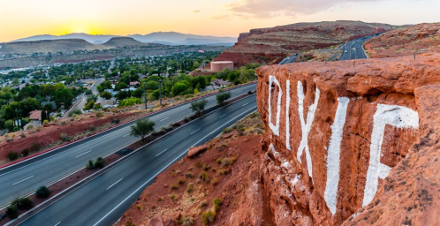 A scenic view of a desert landscape at sunset, featuring a road and a rock with "DIX IT" painted on it.