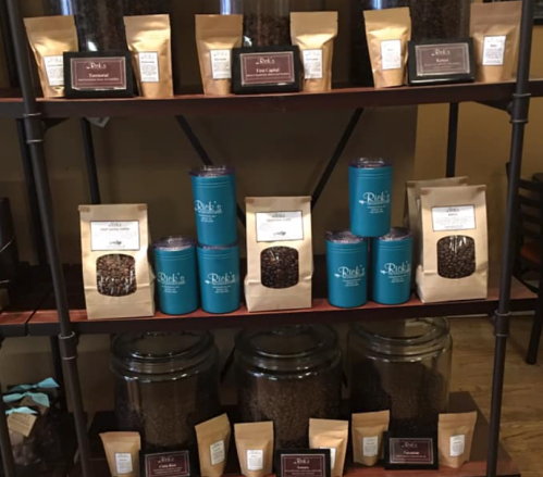 Shelves displaying various coffee bean packages and jars, featuring different brands and types of coffee.