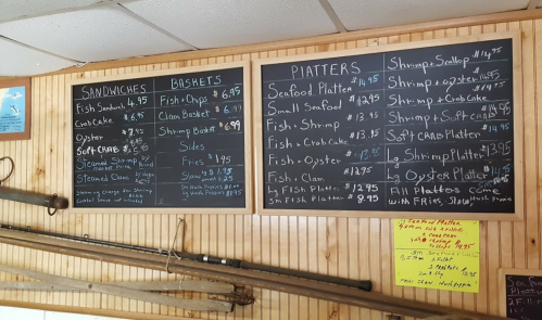 Menu board featuring seafood options like sandwiches, baskets, and platters with prices listed.