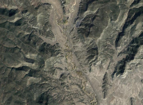 Aerial view of a mountainous landscape with a small settlement named Dawson visible in the center.