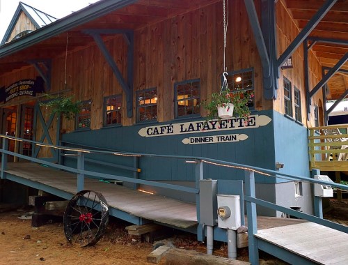 A wooden building with a sign reading "Café Lafayette Dinner Train" and a ramp leading to the entrance.