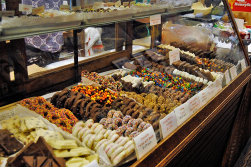 A display case filled with various colorful chocolates and candies, neatly arranged with labels.