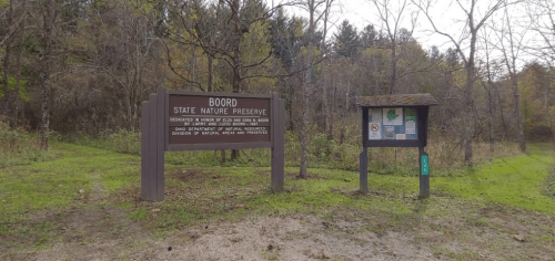 Sign for Bodoro State Nature Preserve, surrounded by trees and nature, with information boards nearby.