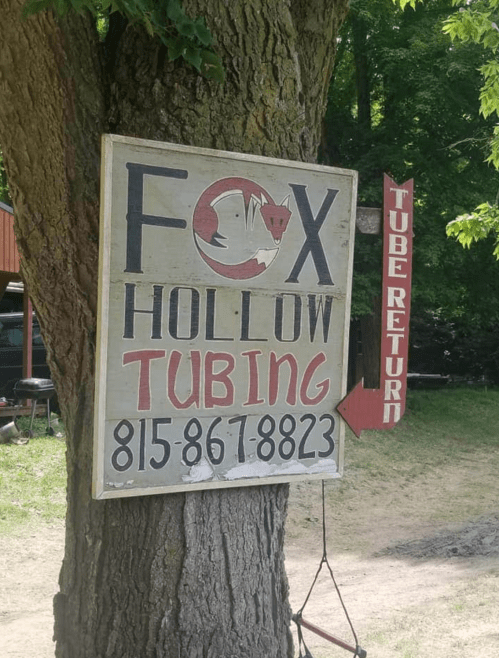 Sign for Fox Hollow Tubing with a fox graphic, featuring contact info and a tube return direction.