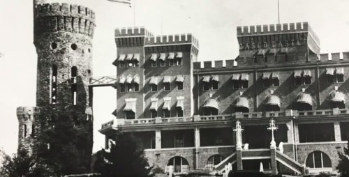 Black and white photo of a castle-like building with a tower, featuring ornate windows and a grand entrance.