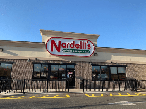 Exterior of Nardelli's Grinder Shoppe, featuring a prominent sign and a clear blue sky above.