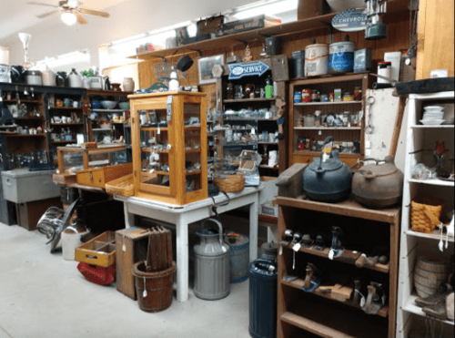 A vintage shop filled with various antiques, glass displays, and wooden shelves showcasing old items and collectibles.