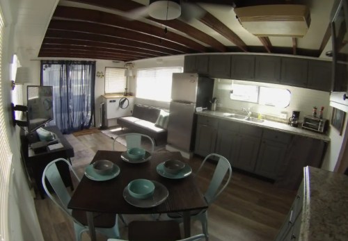 A modern kitchen and dining area with a table set for four, featuring gray cabinets and a cozy seating space.
