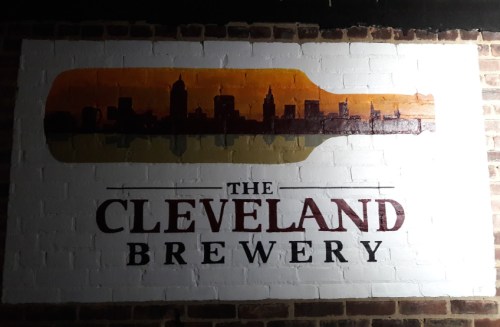 Mural of a skyline inside a bottle silhouette with "The Cleveland Brewery" text on a brick wall.