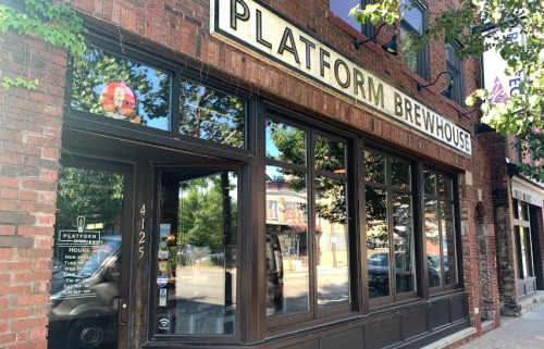Exterior view of Platform Brewhouse, featuring large windows and a brick facade, with trees in the foreground.