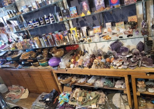 A display of various crystals, bowls, and spiritual items on shelves and tables in a shop.