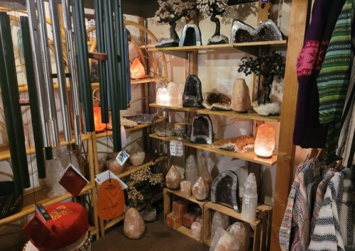 A cozy shop display featuring various crystals, geodes, and decorative items on wooden shelves.