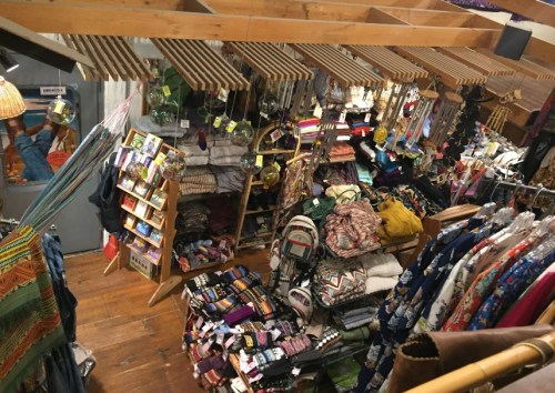 A vibrant store interior filled with colorful clothing, accessories, and handmade items displayed on racks and shelves.