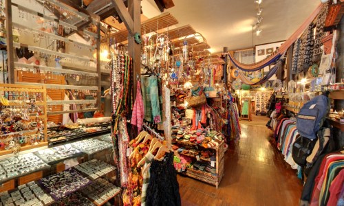 A vibrant shop filled with colorful clothing, jewelry, and accessories, showcasing a variety of handmade items.