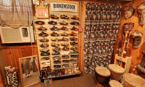 Display of Birkenstock shoes on a wall, with a patterned curtain and wooden decor in a cozy shop setting.