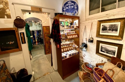 A cozy shop interior featuring a display case of products, framed photos, and a doorway leading to another room.