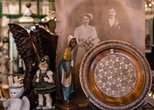 A vintage display featuring an old photograph, decorative plate, and various antique figurines.