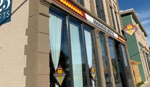 Exterior of Bookhouse Brewing with large windows and decorative signage, set against a clear blue sky.