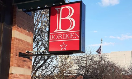 Sign for "Boriken" with a red background and white lettering, displayed outside a brick building.
