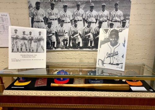 Display case featuring memorabilia, including photos, caps, and a bat, honoring the Cleveland Buckeyes baseball team.