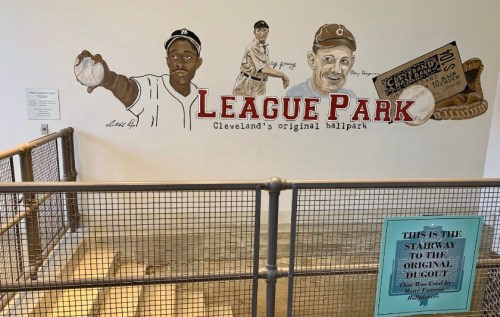Mural at League Park featuring baseball players and a sign for the original dugout stairway.