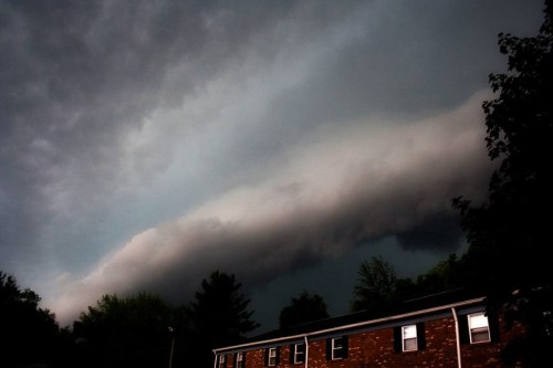 Dark storm clouds roll over a building, creating a dramatic sky with a looming, ominous atmosphere.