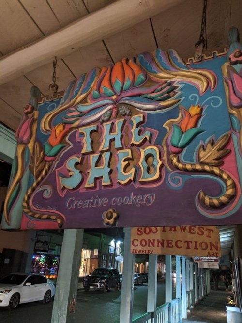 Colorful sign for "The Shed" featuring artistic designs and the text "Creative Cookery" beneath it.