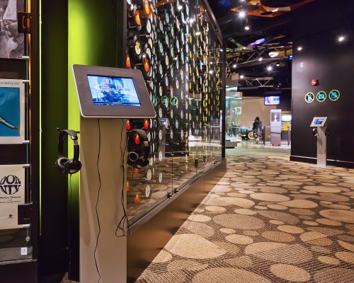 A museum hallway featuring interactive displays, vinyl records, and audio stations with headphones.