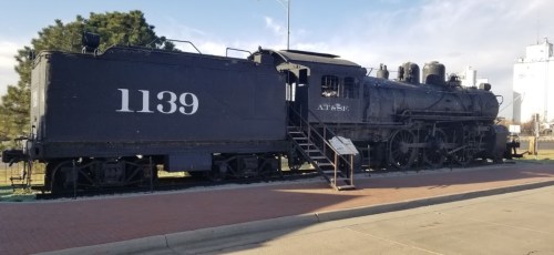 A vintage black steam locomotive, numbered 1139, displayed outdoors with a sign nearby.