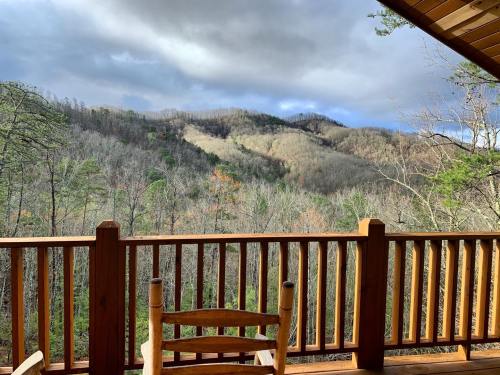 A wooden balcony overlooks a misty mountain landscape with bare trees and cloudy skies.