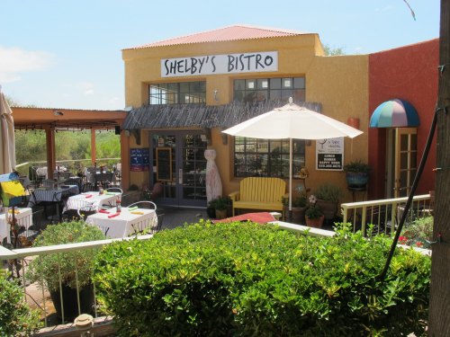 Exterior of Shelby's Bistro featuring colorful walls, outdoor seating, and a sunny patio with plants.