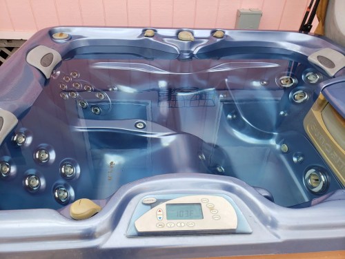 A blue hot tub with jets and a digital control panel displaying a temperature of 103°F.