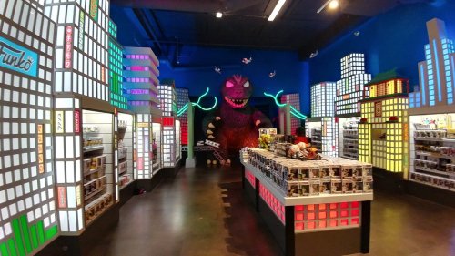 A vibrant toy store with colorful cityscape displays and a large monster figure in the background.