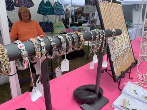A display of bracelets and necklaces for sale at a market, with a vendor in the background.