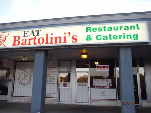 Sign for Bartolini's Restaurant & Catering, featuring "EAT" and "OPEN" in bright letters on a storefront.