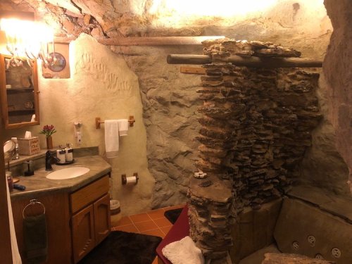 A rustic bathroom with stone walls, a sink, and a unique stone feature, creating a cozy, natural atmosphere.
