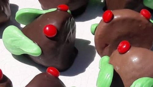 Chocolate-covered treats shaped like small Christmas trees, decorated with green icing and red candy dots.